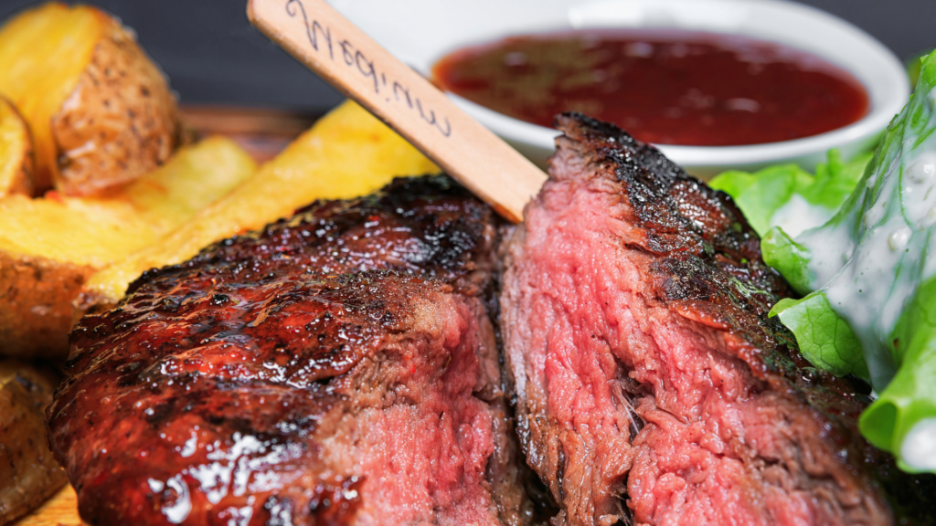 Ein saftiges Rumpsteak mit Fettrand, perfekt unter einem Beefer bei 800 Grad gegart, serviert mit einer frischen Salatgarnitur.